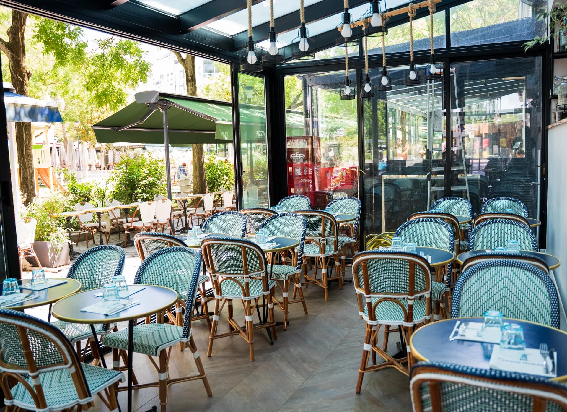 La terrasse couverte de la Crêperie Madeleine sous sa verrière, chaises bistrot bleu et vert